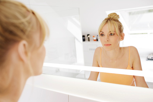 Woman looking at her mirror image in the bathroom